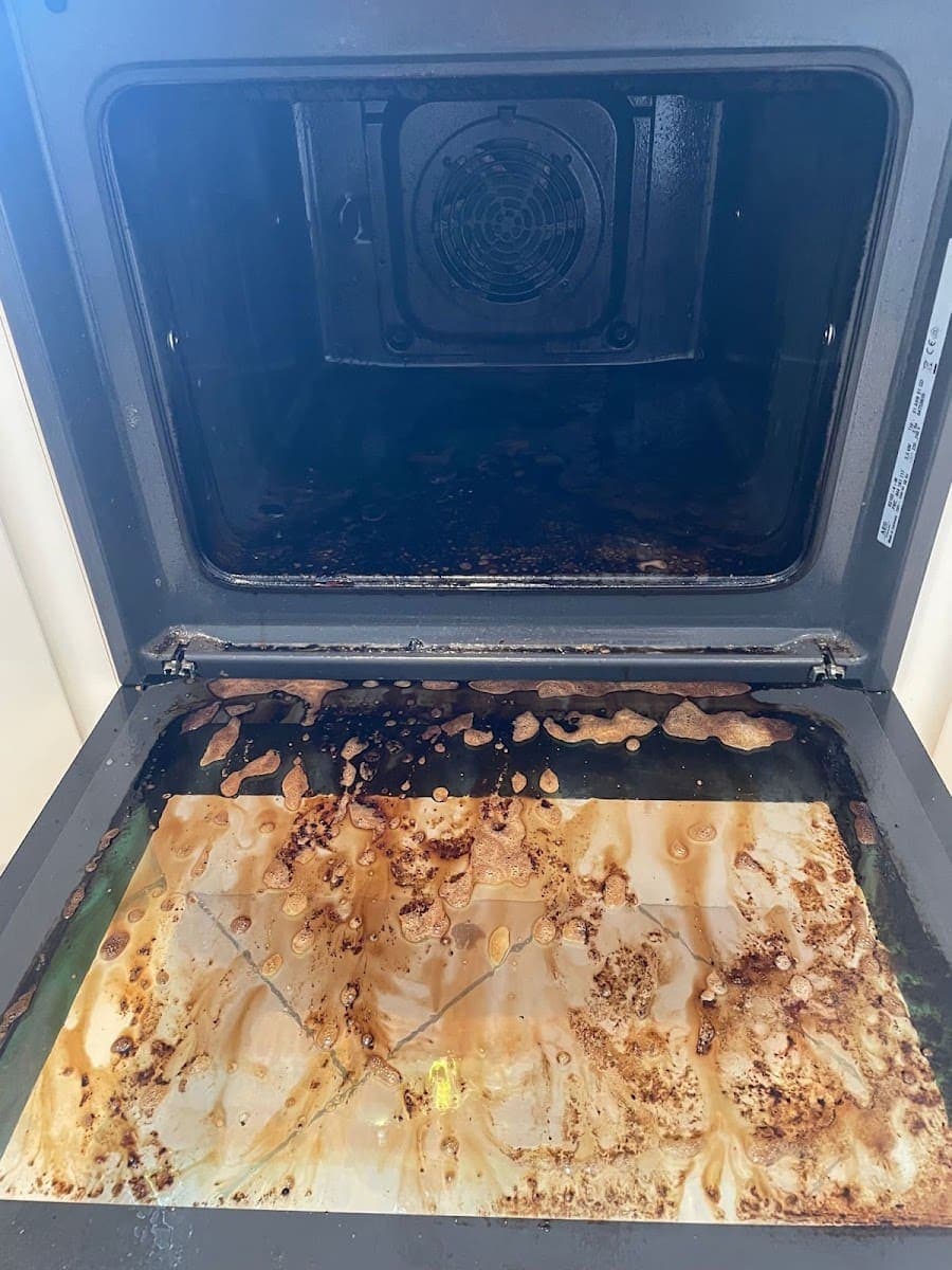 Oven before cleaning with baked-on grease across the base and door glass